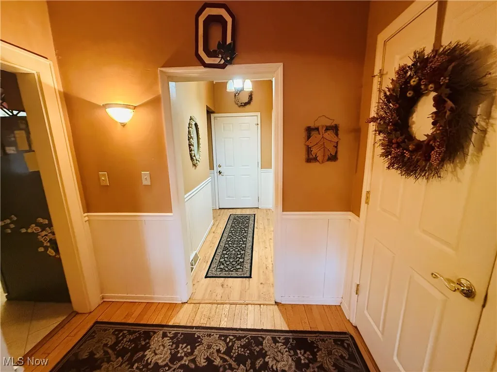 Doorway to outside with wainscoting and light wood-style flooring