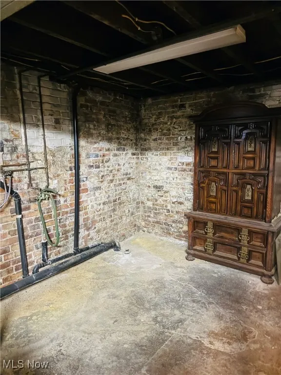 Unfinished below grade area featuring brick wall