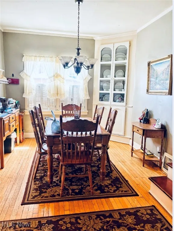 Dining room with ornamental molding, an inviting chandelier, and hardwood / wood-style floors