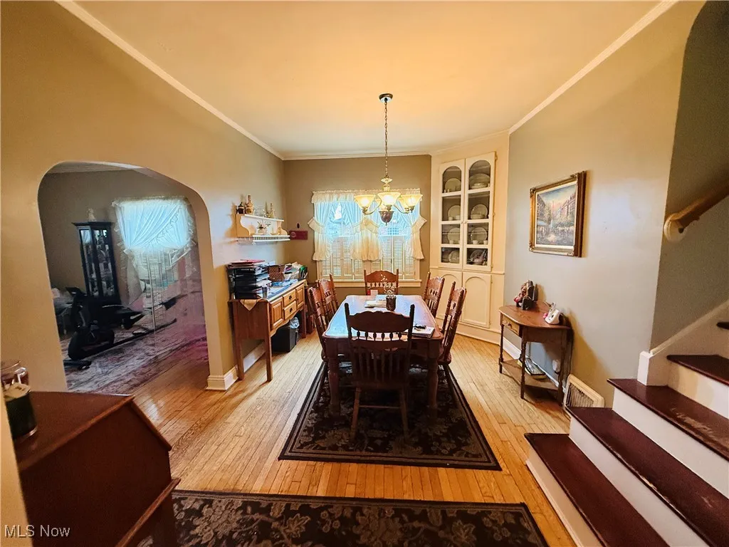 Dining room with built in features, an inviting chandelier, light wood-style flooring, stairs, and arched walkways