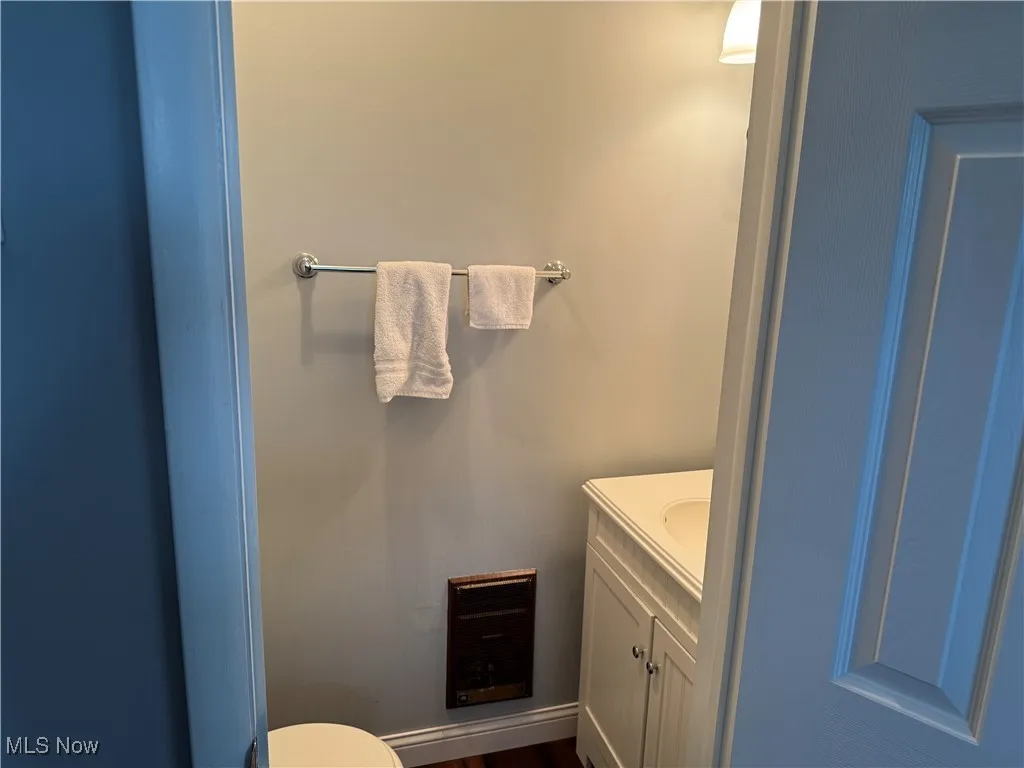 Half bathroom featuring toilet, vanity, and wood finished floors