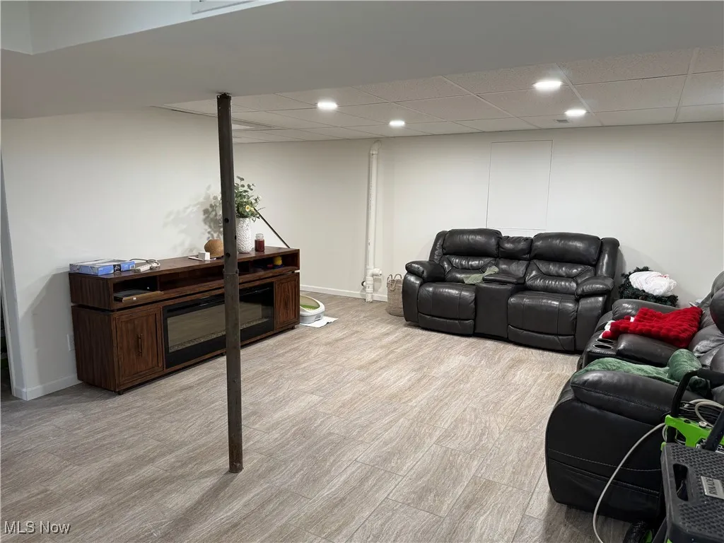 Living area featuring a paneled ceiling, baseboards, and recessed lighting