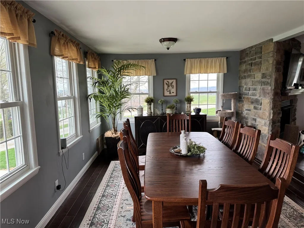 Dining space with baseboards, a fireplace, and dark wood-style floors