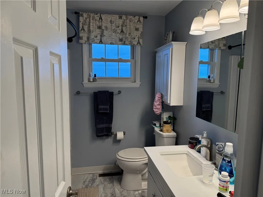 Bathroom featuring toilet, marble finish floor, vanity, and baseboards