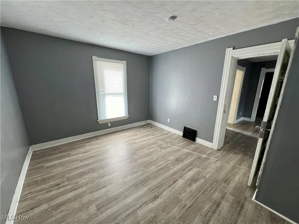 Spare room featuring baseboards, wood finished floors, and a textured ceiling