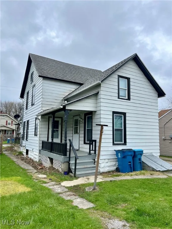 View of front of home with a porch, a shingled roof, and a front lawn