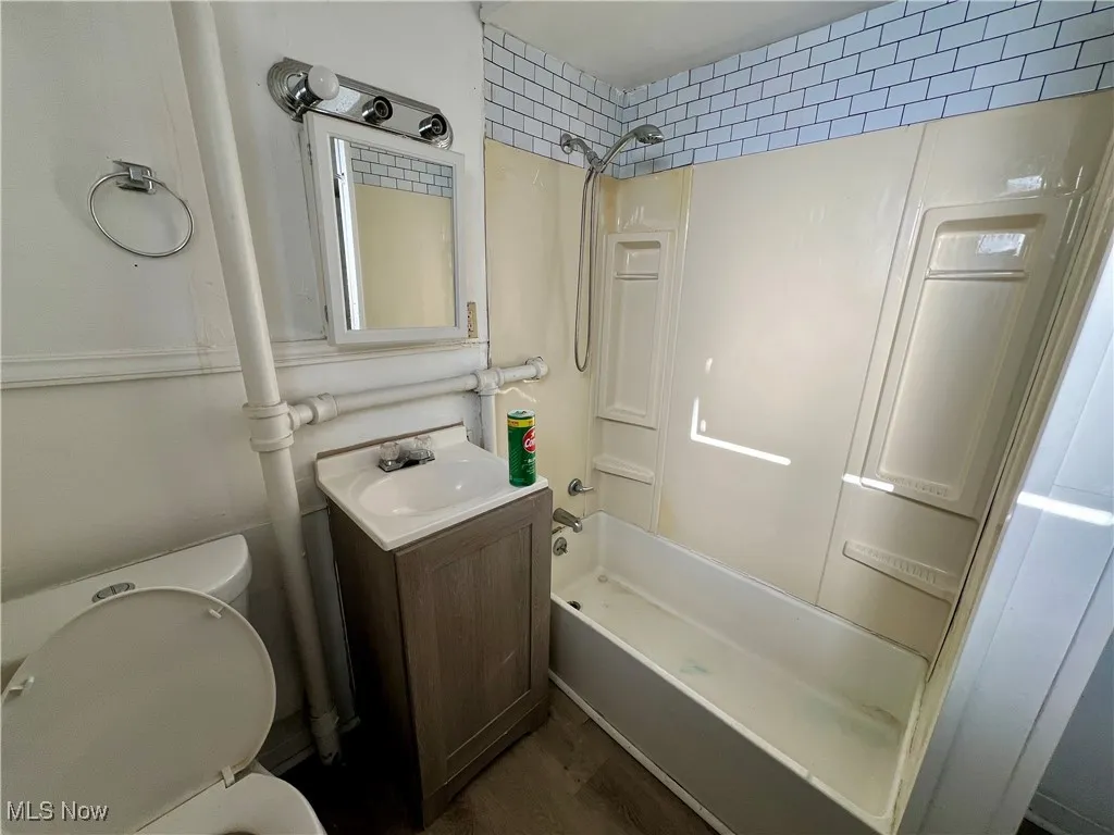 Full bathroom with vanity,  shower combination, toilet, and wood finished floors