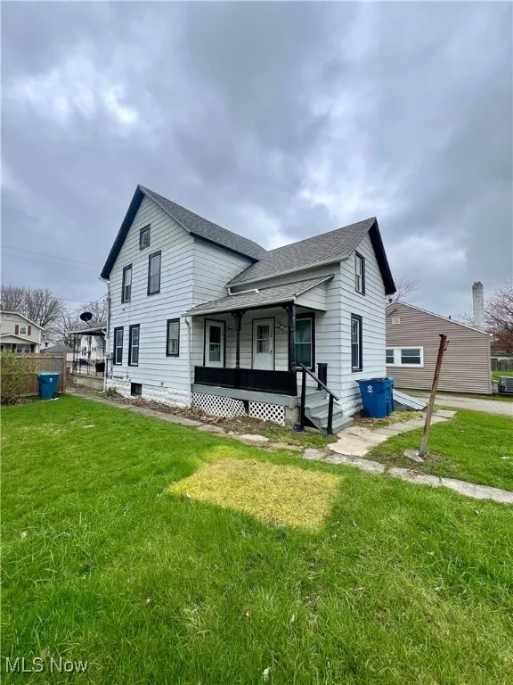 Rear view of property featuring a yard, a shingled roof, and covered porch
