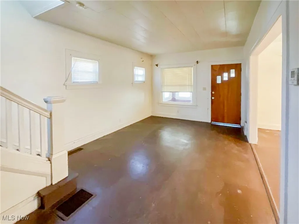 Foyer with concrete floors, visible vents, and baseboards