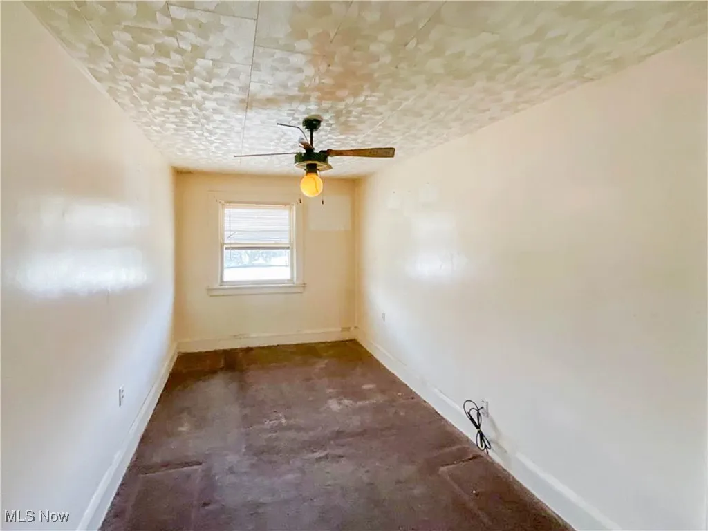 Empty room with ceiling fan, baseboards, and unfinished concrete flooring