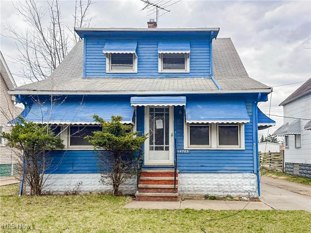 Bungalow-style house with roof with shingles, entry steps, fence, and a front lawn