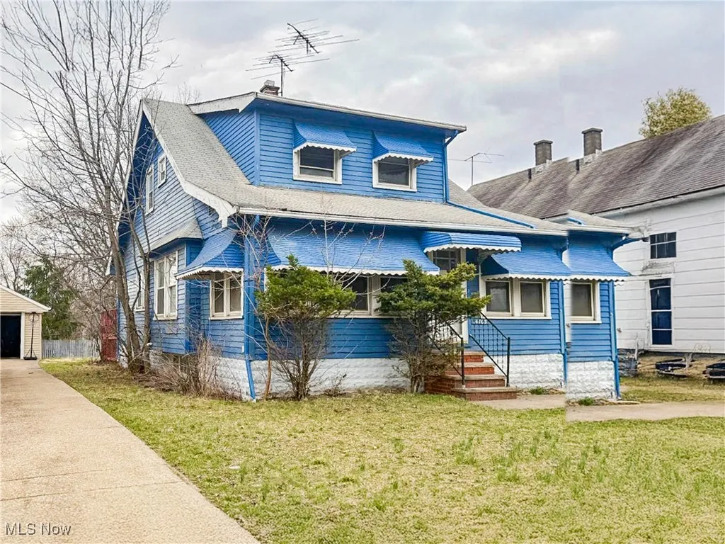 View of front of home with a front yard and a shingled roof