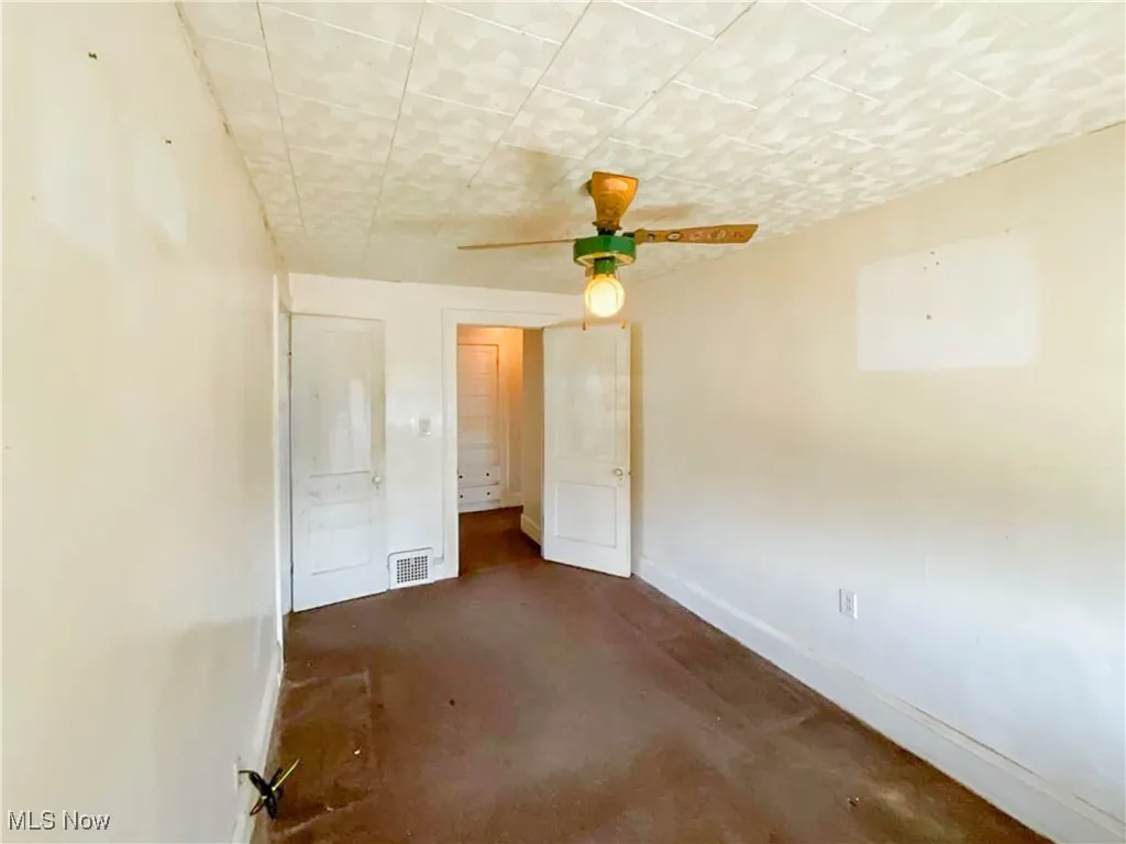 Unfurnished bedroom featuring concrete floors, visible vents, baseboards, and ceiling fan