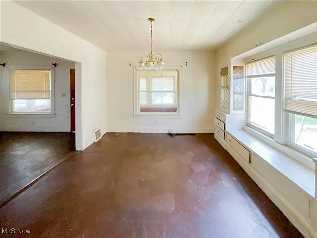 Unfurnished dining area with visible vents, baseboards, an inviting chandelier, and finished concrete flooring