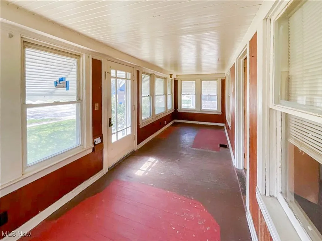 Unfurnished sunroom with baseboards, visible vents, and a wealth of natural light