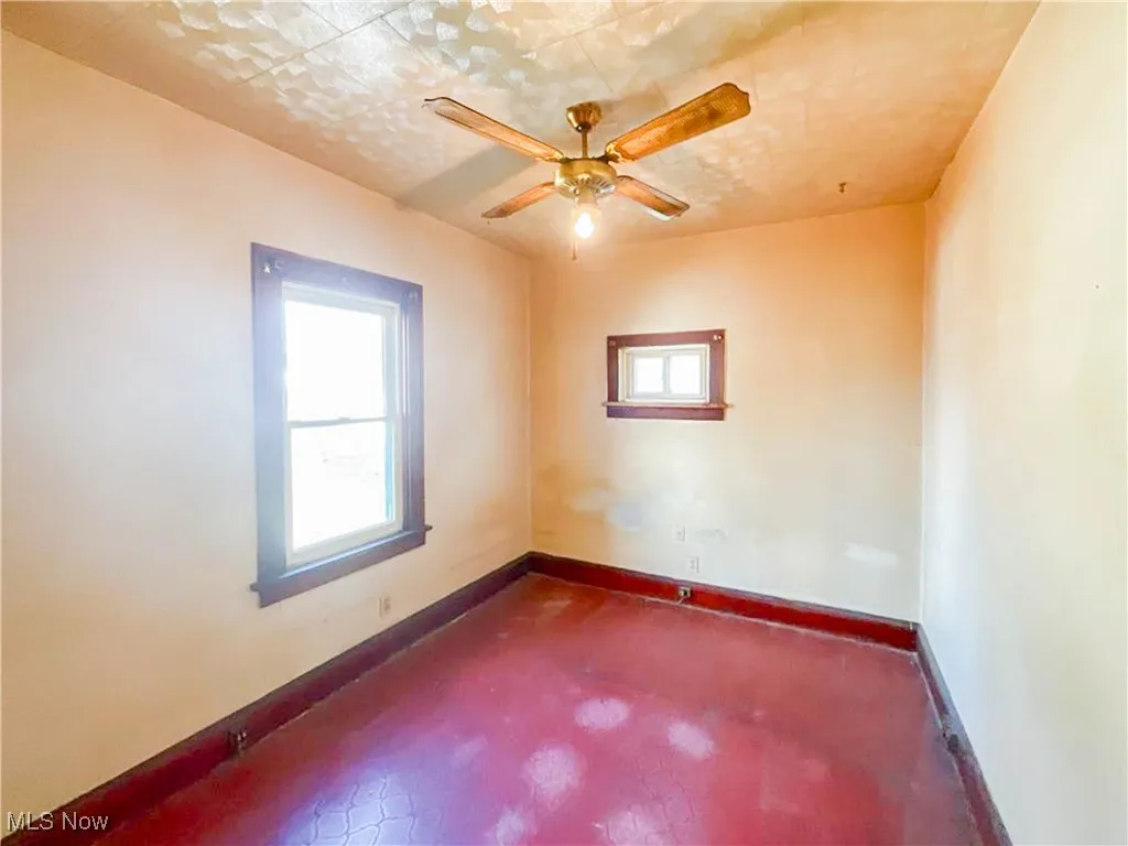 Unfurnished room featuring baseboards, a ceiling fan, and a healthy amount of sunlight