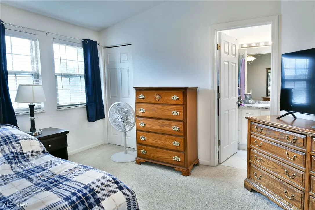 Bedroom featuring light colored carpet, baseboards, and ensuite bathroom