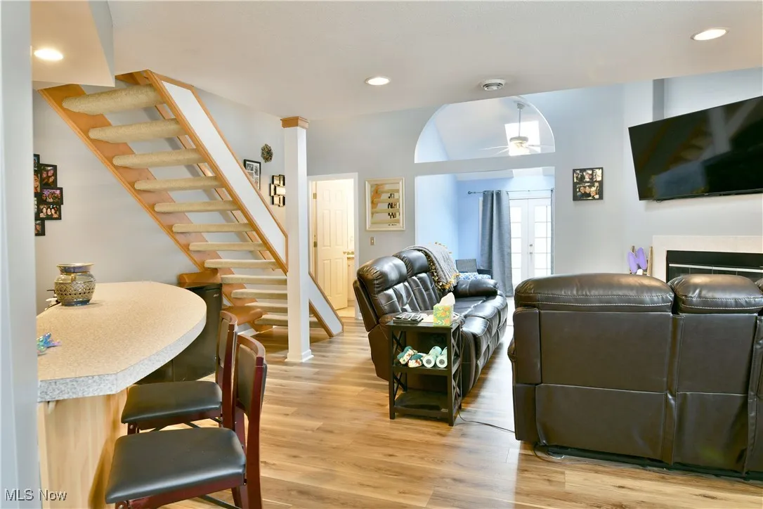 Living area featuring light wood-style floors, ceiling fan, a fireplace, recessed lighting, and stairway
