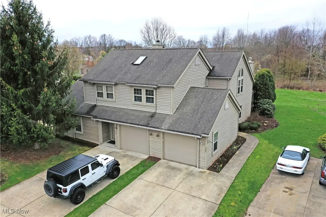 Traditional home featuring concrete driveway, roof with shingles, a chimney, and a front lawn