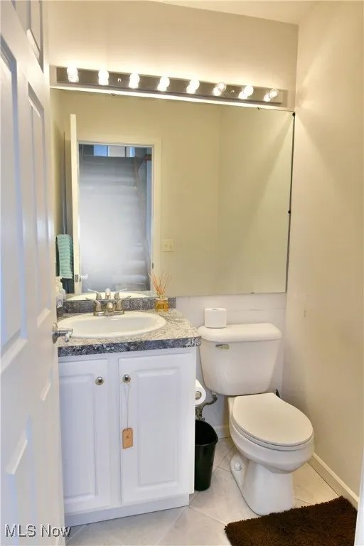 Half bathroom featuring toilet, tile patterned floors, and vanity