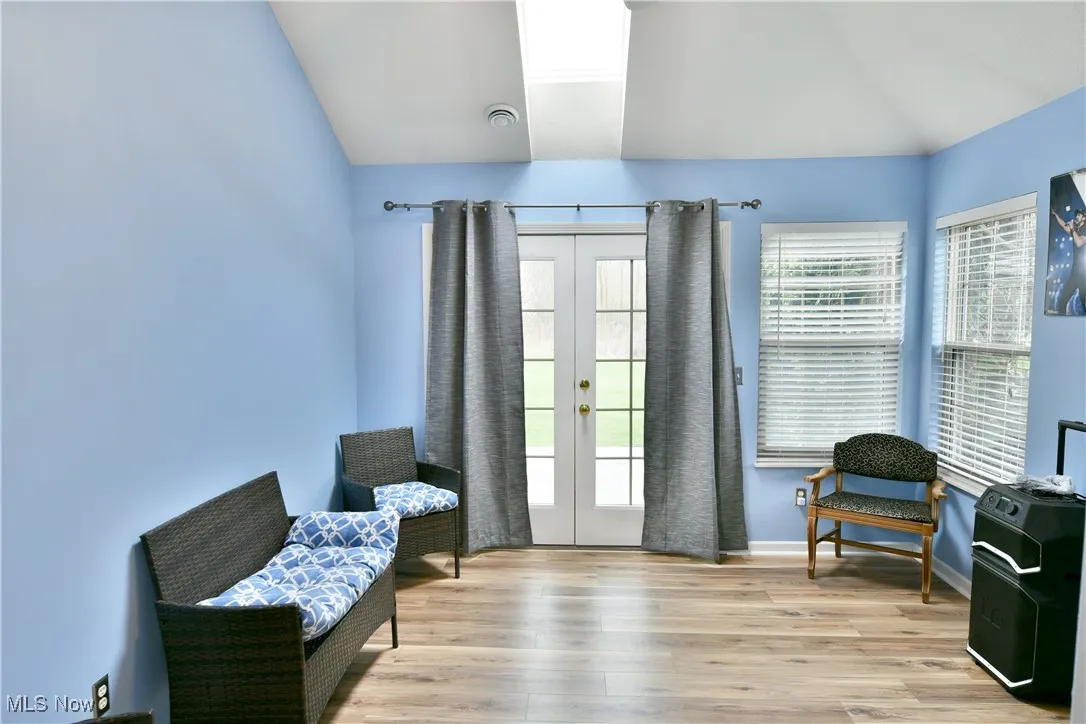 Living area with french doors, wood finished floors, baseboards, and lofted ceiling