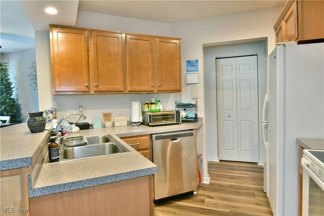 Kitchen with light wood-style floors, white appliances, recessed lighting, a sink, and a toaster