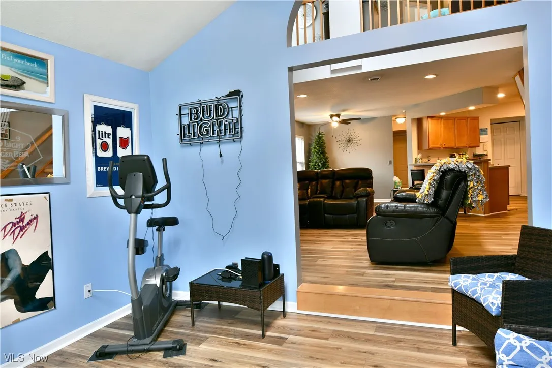 Exercise room featuring light wood-style flooring, high vaulted ceiling, and baseboards