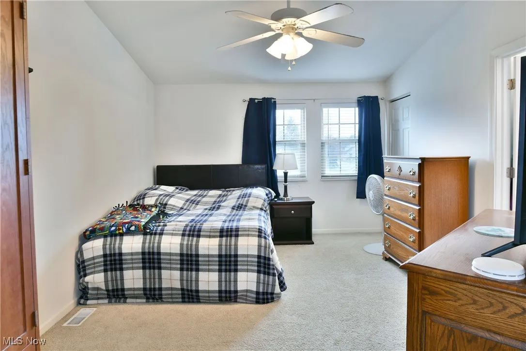 Carpeted bedroom with visible vents, baseboards, a ceiling fan, and vaulted ceiling