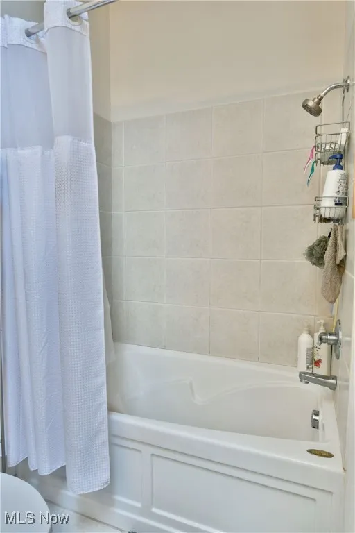 Bathroom featuring toilet and shower / bath combo with shower curtain