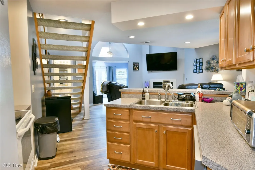 Kitchen with a peninsula, light wood-type flooring, a sink, light countertops, and open floor plan