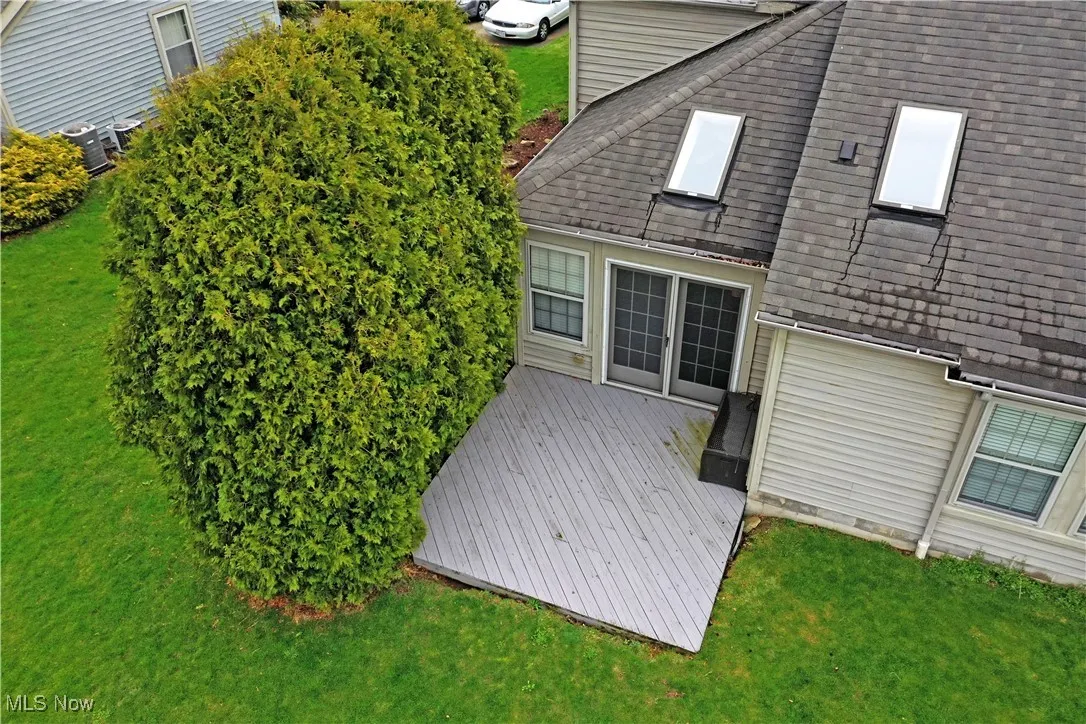 Rear view of house with central AC, a shingled roof, a deck, and a lawn