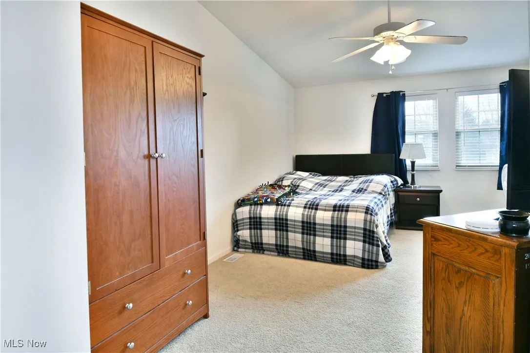 Bedroom featuring a ceiling fan, light colored carpet, and vaulted ceiling