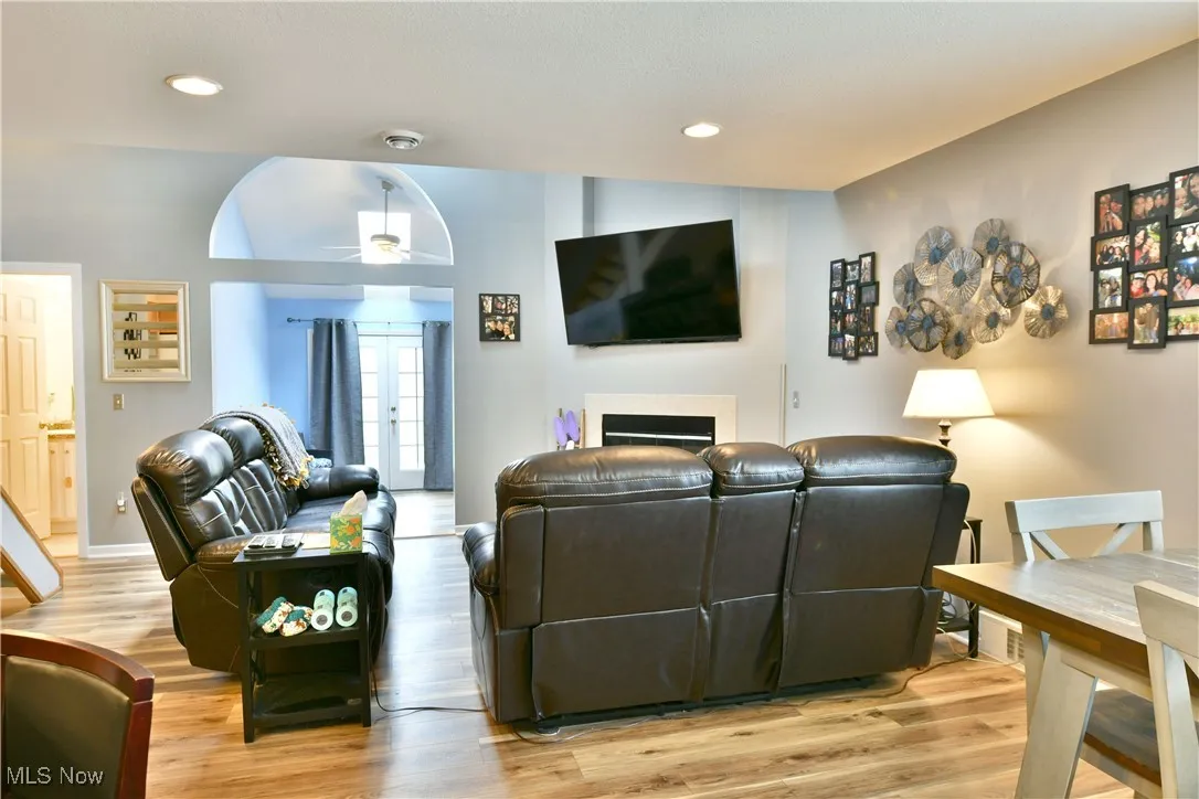 Living room with a fireplace, light wood-type flooring, and a ceiling fan