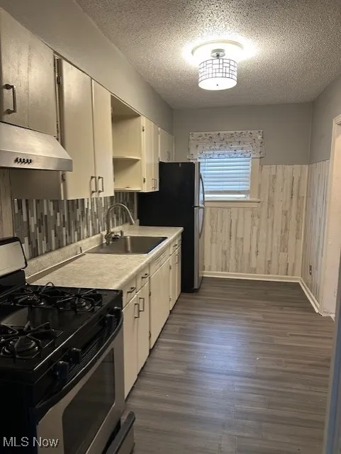 Kitchen with stainless steel gas range, a textured ceiling, a sink, and open shelves