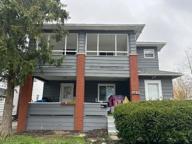 Back of property featuring covered porch and a balcony