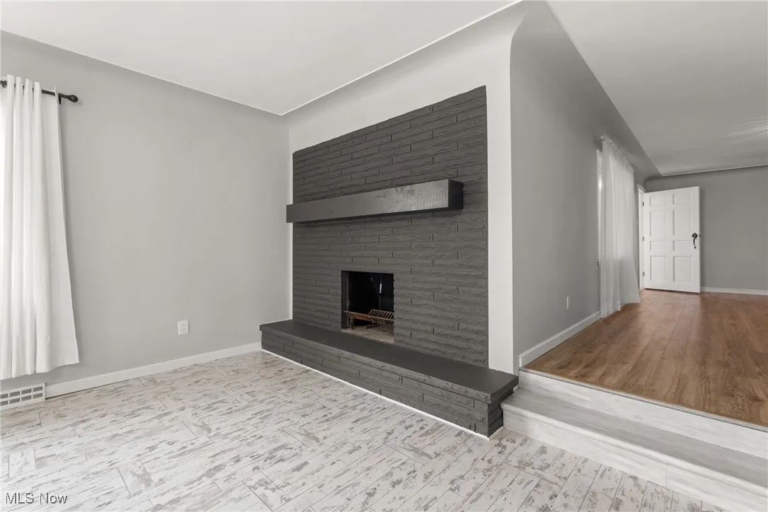 Unfurnished living room featuring visible vents, baseboards, wood finished floors, and a fireplace