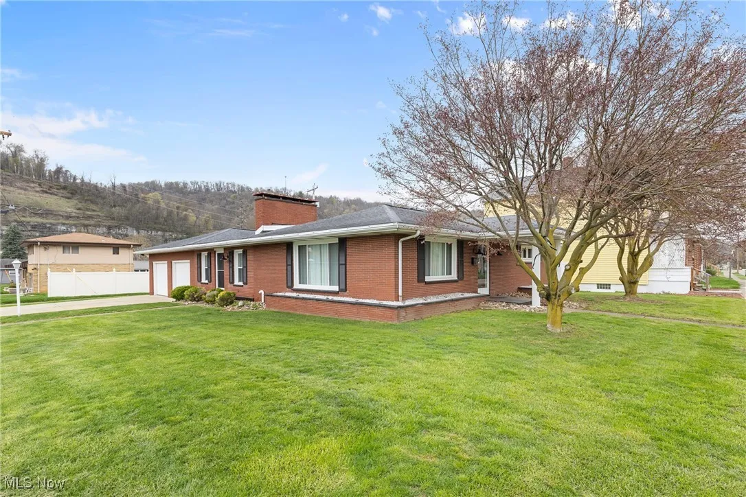 Ranch-style house featuring fence, a front lawn, brick siding, an attached garage, and driveway