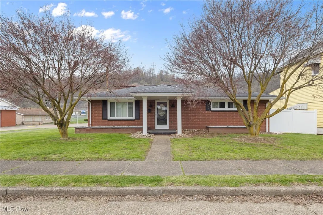View of front of home featuring brick siding, a front yard, and fence