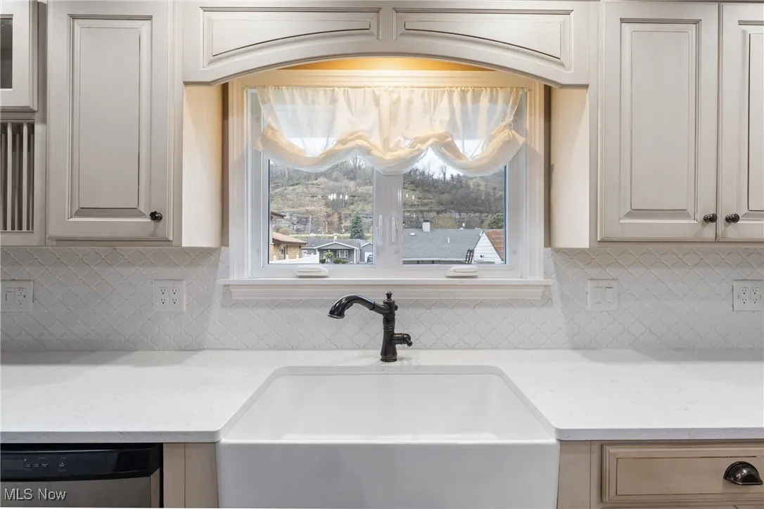 Details featuring a sink, backsplash, dishwasher, and light stone countertops