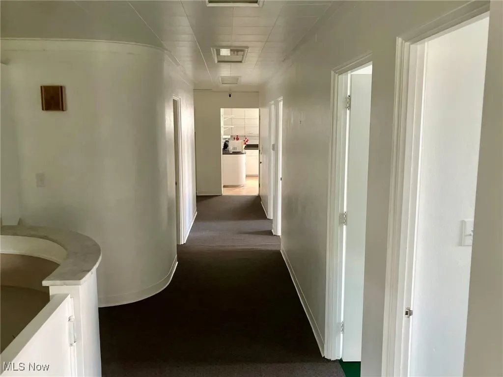 Hallway featuring attic access, baseboards, and visible vents
