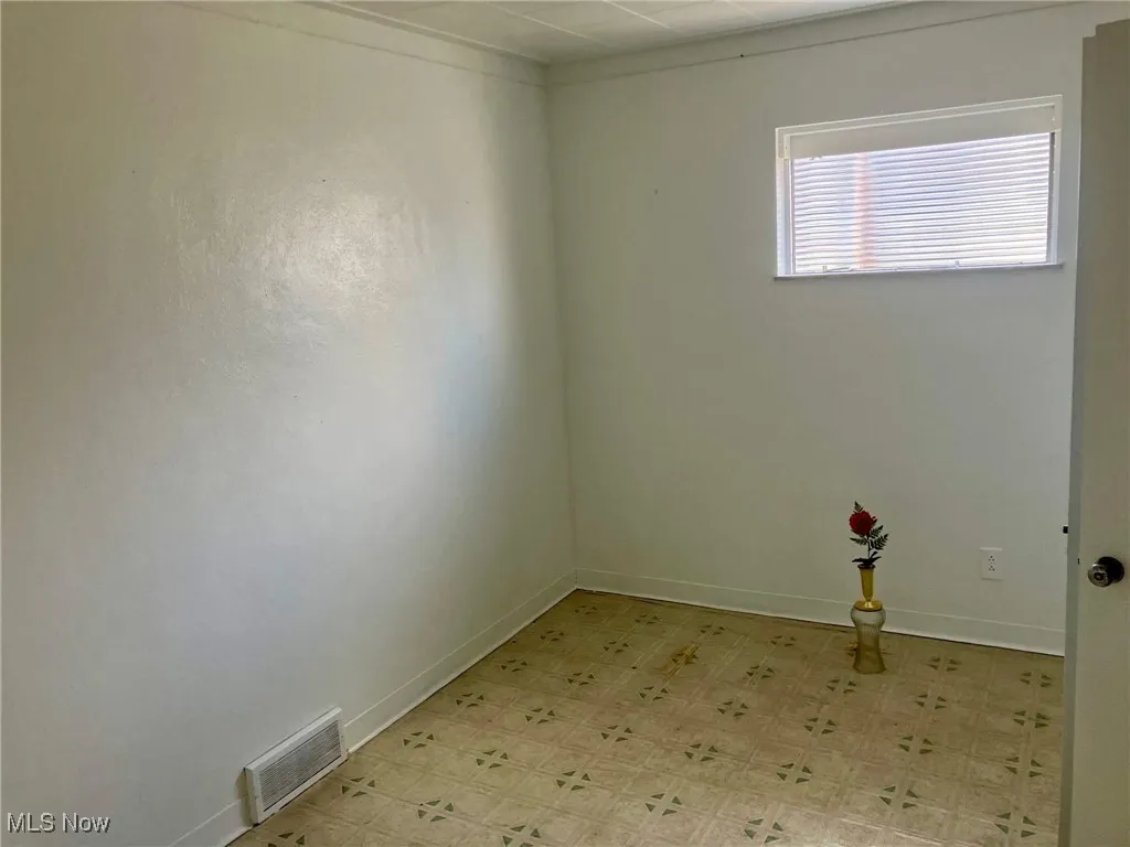 Empty room with baseboards, visible vents, and light floors