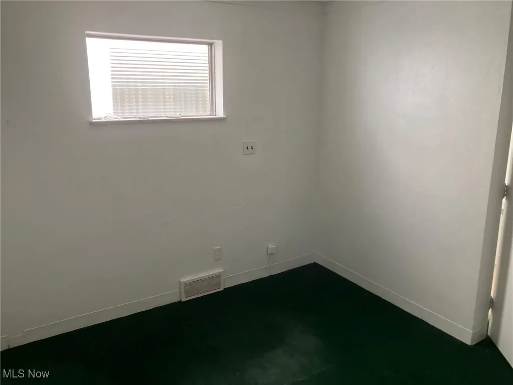 Unfurnished room featuring baseboards, visible vents, and dark colored carpet