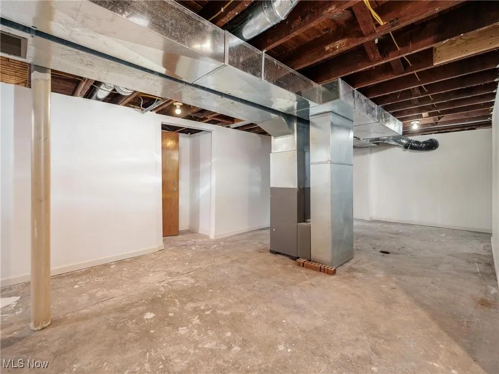 Unfinished below grade area featuring visible vents and heating unit