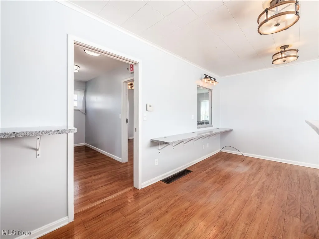 Unfurnished room featuring baseboards, light wood-style flooring, visible vents, and ornamental molding