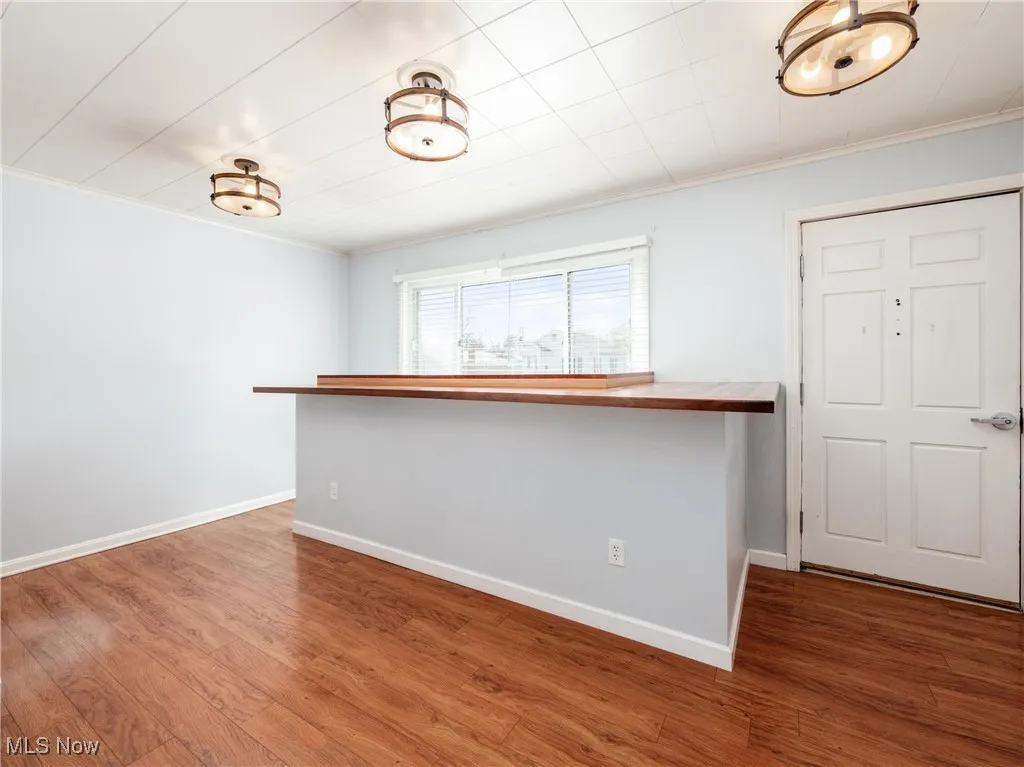 Empty room featuring crown molding, baseboards, and wood finished floors