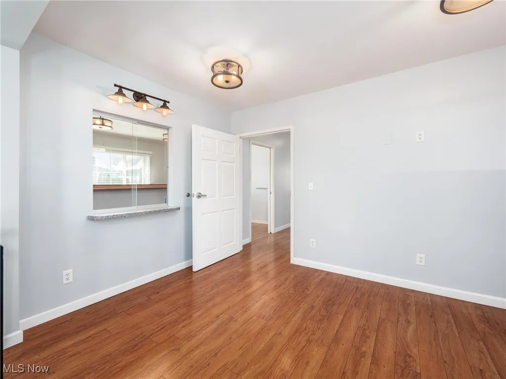 Unfurnished room with wood finished floors and baseboards