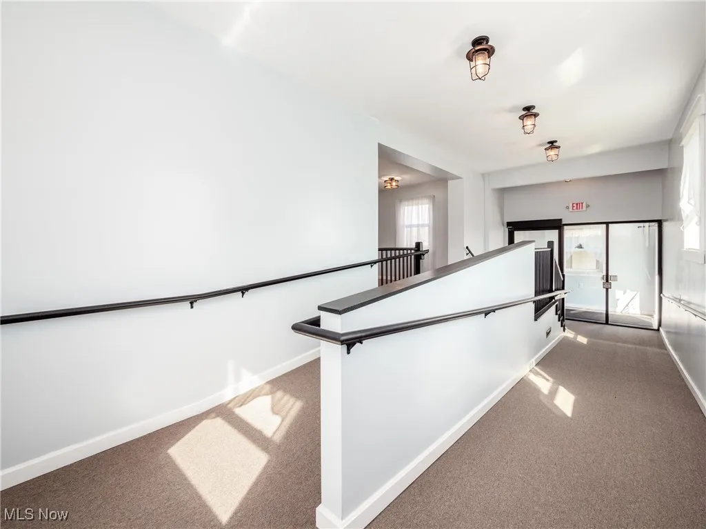 Hallway with carpet flooring, an upstairs landing, and baseboards