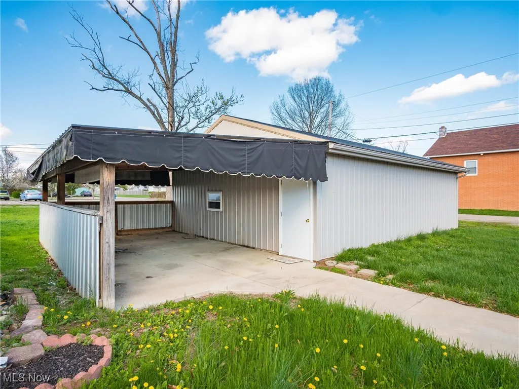 View of outbuilding featuring concrete driveway and a carport