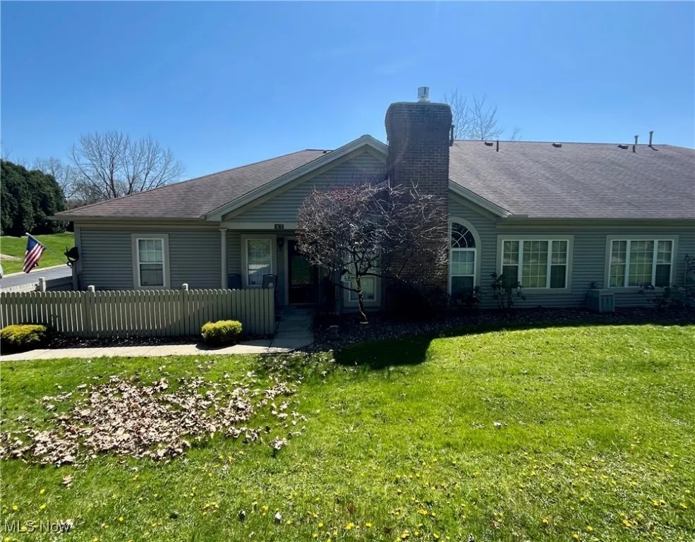 View of front facade featuring a shingled roof, a chimney, a front lawn, and a fenced front yard