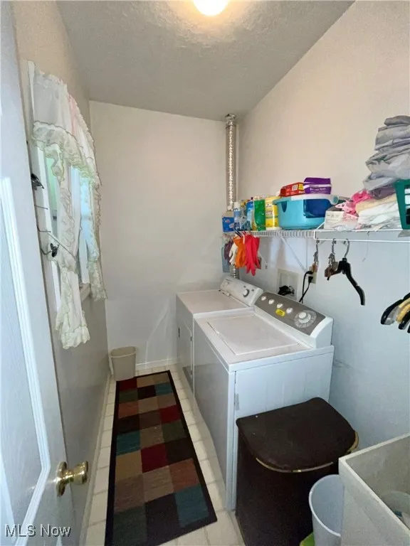 Laundry room featuring separate washer and dryer, laundry area, and a textured ceiling